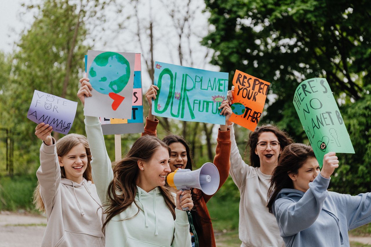 Group of young activists holding placards and megaphone during an outdoor environmental protest.
