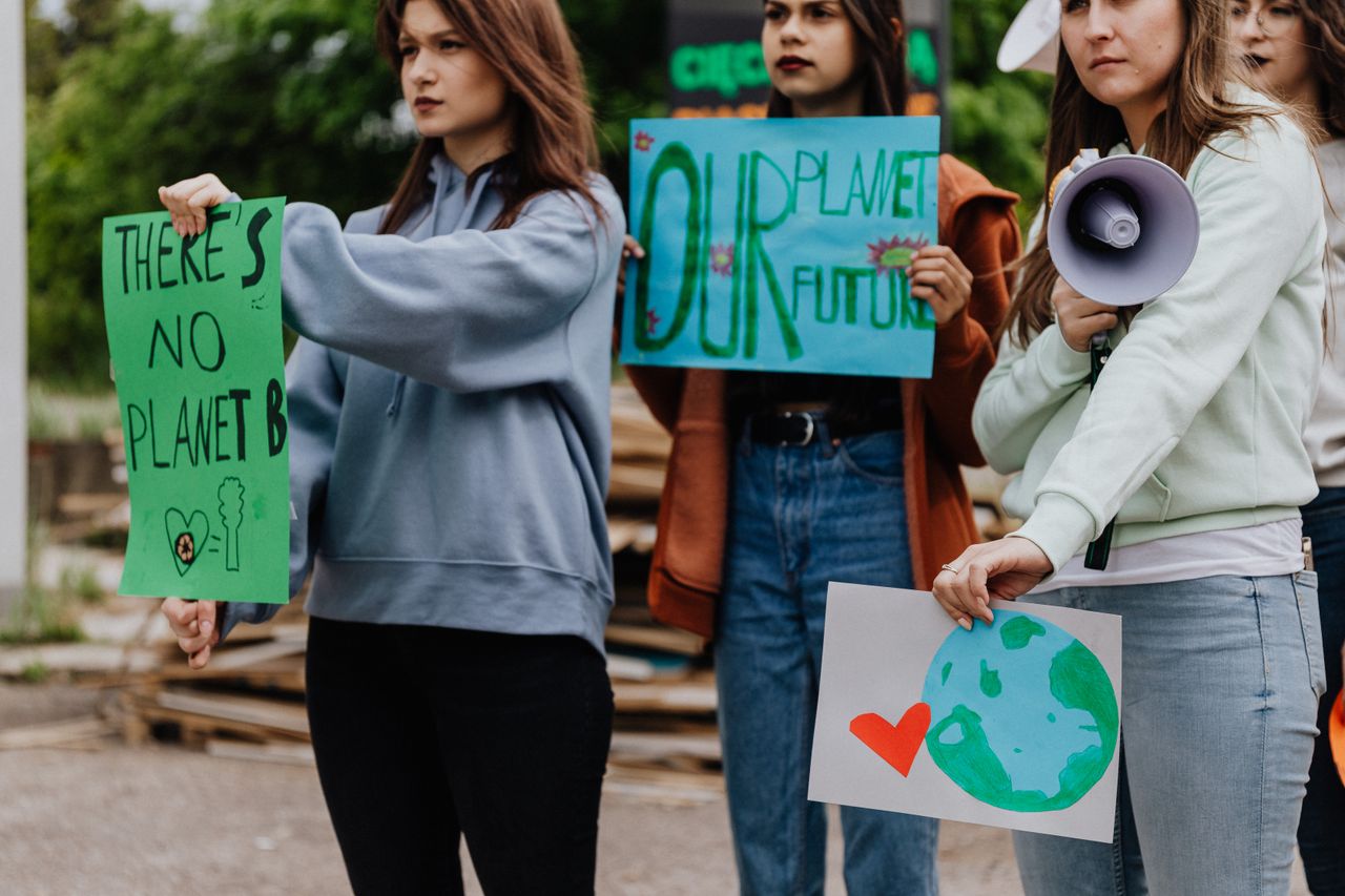 Group of young women at a climate change protest holding handmade signs.